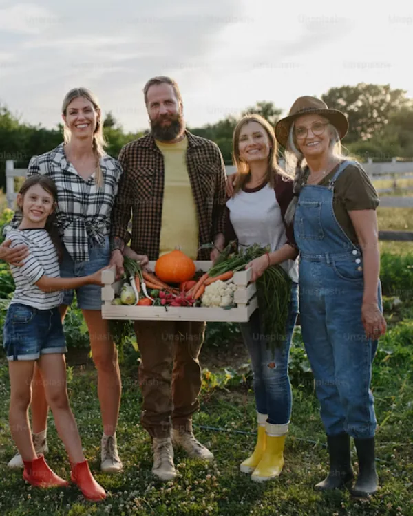 Una famiglia sorridente nell'orto con una cassetta di verdure appena raccolte
